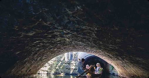 Shared punting tour passing under a stone bridge