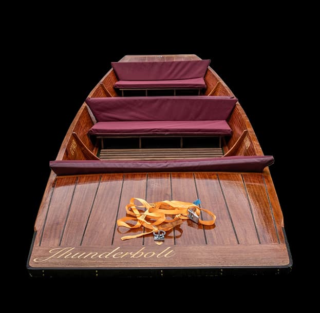 Thunderbolt punt with comfortable maroon cushions on a polished wooden deck